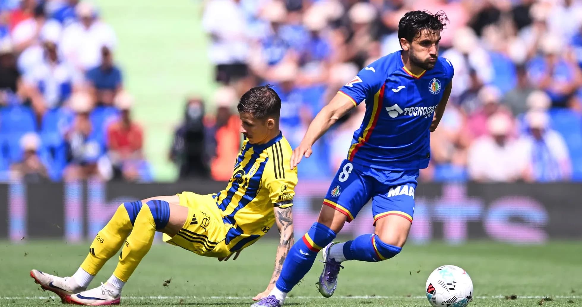 Getafe player tackling Oviedo opponent during match