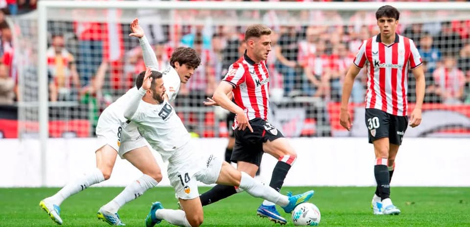 Athletic Club player dribbling past Valencia defenders