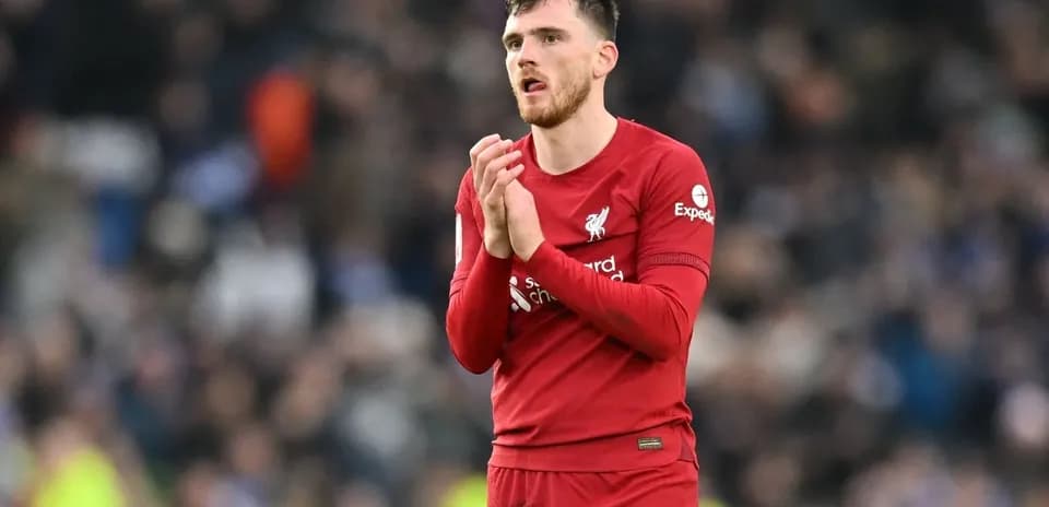 Player in red jersey applauding fans at stadium