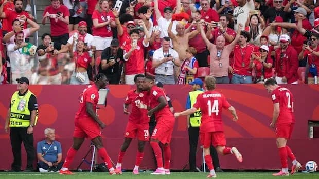 Players celebrating a goal with cheering fans in background Players celebrating a goal with cheering fans in background