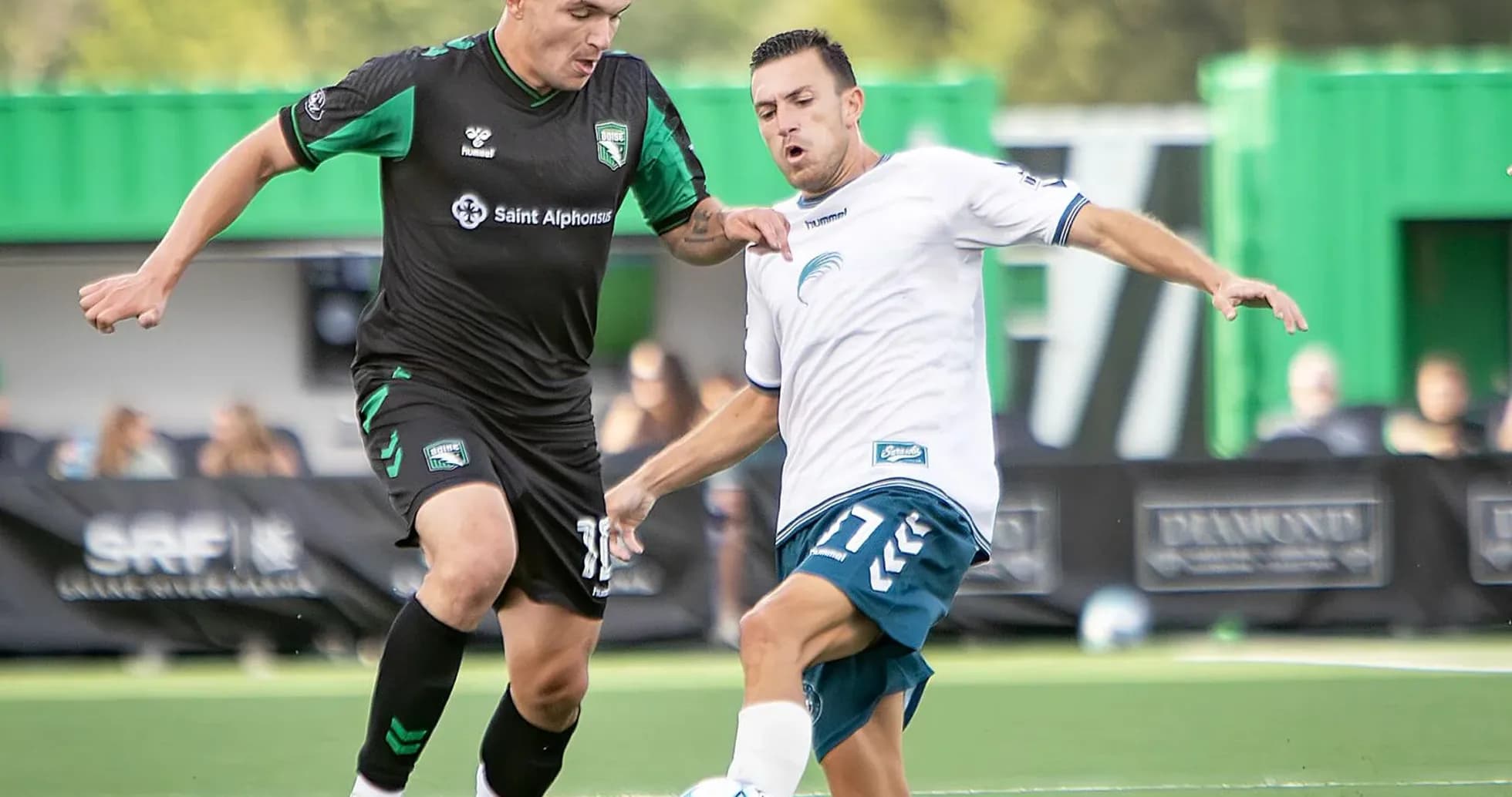 Two players competing for the ball in football match Two players competing for the ball in football match