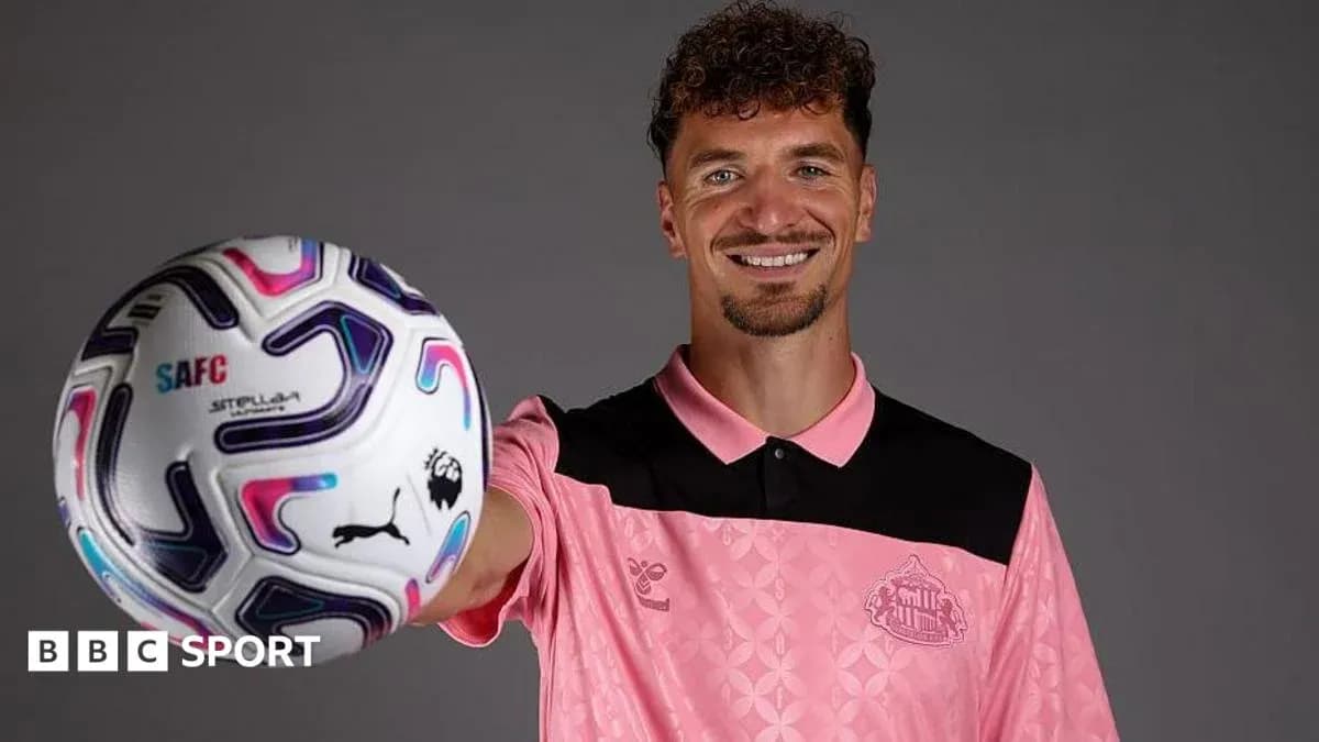 Player holding a football while smiling at camera Player holding a football while smiling at camera